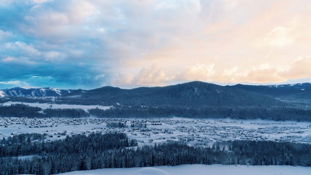Un village serein niché dans des montagnes enneigées par une journée d'hiver claire.