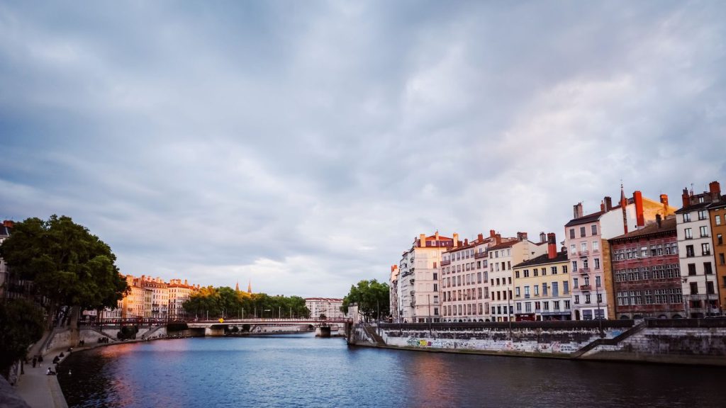 Relations économiques franco-italiennes — vue panoramique des bâtiments colorés se reflétant sur une rivière de Lyon à la lumière du soir