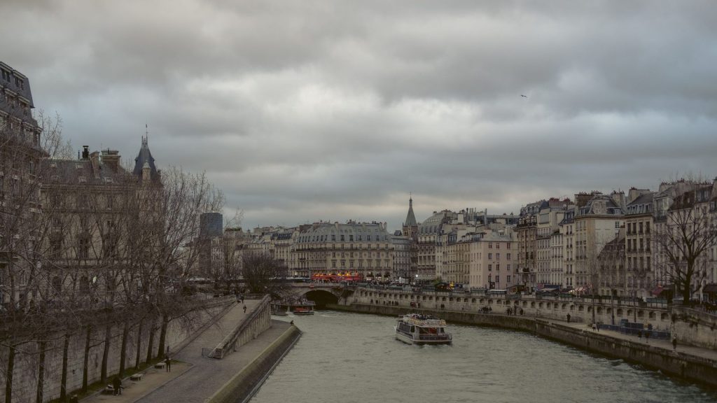 Autodomestication des managers — une vue captivante de la Seine avec une architecture parisienne emblématique et des bateaux-mouches sous un ciel nuageux