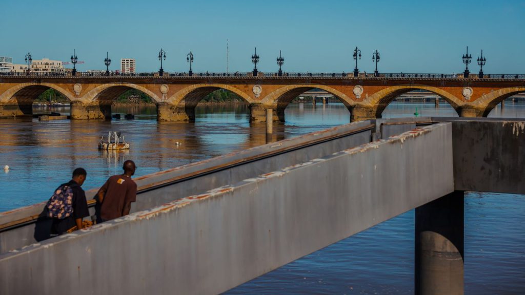 Forêts françaises face au climat — vue du pont historique de Pierre à Bordeaux, enjambant la Garonne avec des personnes au premier plan