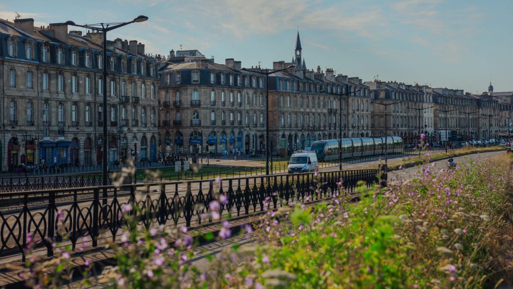Droit de vote des étrangers — vue charmante de bâtiments historiques et de tramway à Bordeaux, France, avec des fleurs vibrantes au premier plan