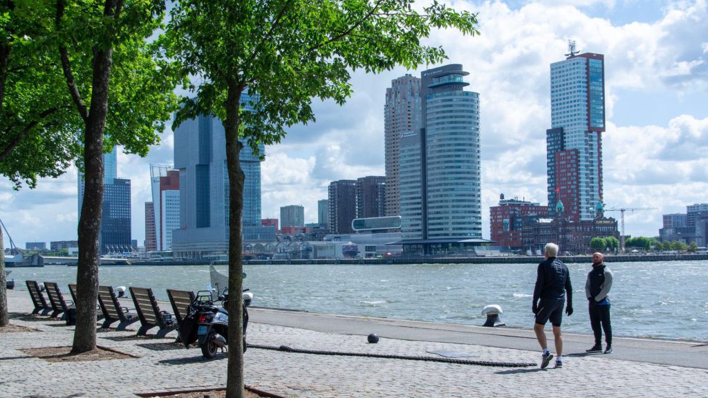 Adhésion de l’Islande à l’UE — des personnes profitant d'une promenade au bord de la rivière avec la silhouette de la ville de Rotterdam en arrière-plan