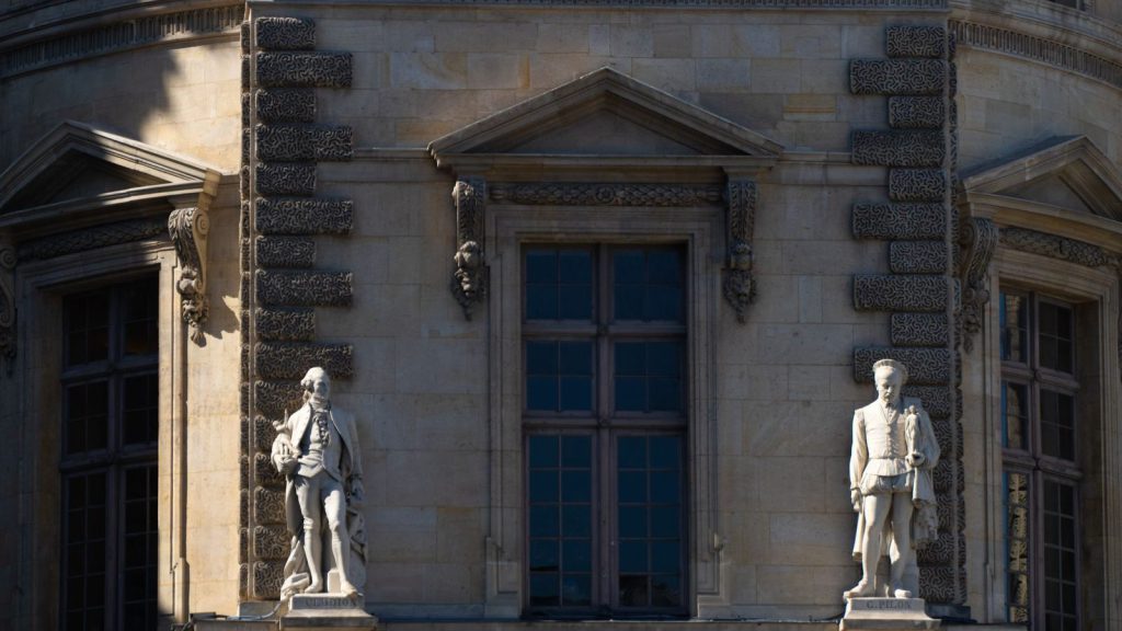 Aires d’accueil des Voyageurs — gros plan sur des détails architecturaux et des statues sur la façade d'un bâtiment historique parisien