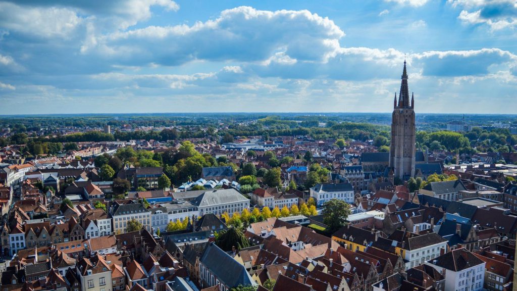 Vente de TAP — prise de vue aérienne du paysage urbain de Bruges présentant le célèbre Beffroi sous un ciel partiellement nuageux
